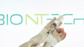 Preparing BioNTech vaccine injection. A doctor prepares coronavirus vaccine for injection against BioNTech logo photo