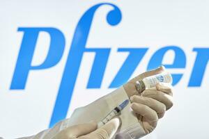 Preparing Pfizer vaccine injection. A doctor prepares coronavirus vaccine for injection against Pfizer logo photo