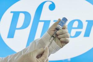 Preparing Pfizer vaccine injection. A doctor prepares coronavirus vaccine for injection against Pfizer logo photo