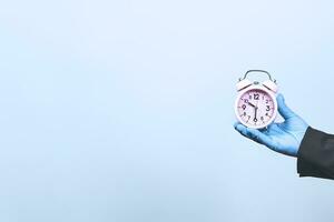 Covid-19 - Time ticking bomb. Businessman holds alarm clock. Quarantine hurting business. Business at home photo