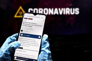 Doctor checking news on smartphone about COVID-19 situation in Germany photo