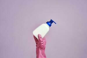 Female hand in rubber gloves holding liquid soap gel bottle photo