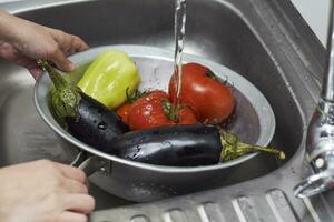 mujer Lavado recién escogido orgánico vegetales en colador antes de preparando sano ensalada foto