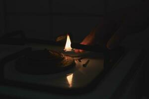 Woman trying to turn on gas with a match flame photo