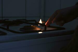 Woman trying to turn on gas with a match flame photo