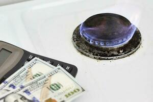 Burning gas stove burner, calculator and money photo