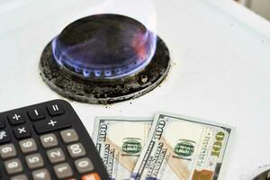 Burning gas stove burner, calculator and money photo