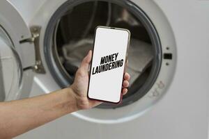 Money laundering concept - A person holding smartphone over washing machine photo