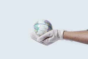 médico manos en médico quirúrgico guantes sostener miniatura el tierra globo foto