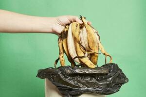 Woman thorwing banana peels in trash can photo