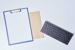 Empty clipboard with white paper, envelope and keyboard photo