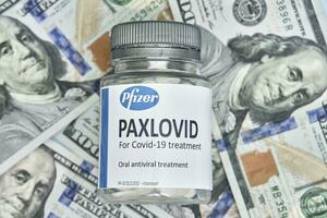 Pile of us dollars and Paxlovid new Pfizer oral drug against Covid-19 photo