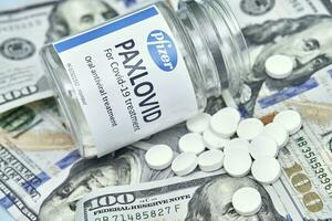 Pile of us dollars and Paxlovid new Pfizer oral drug against Covid-19 photo