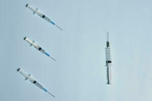 Syringes on bright blue. Symbol of three Covid-19 booster shot photo