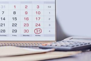 Calendar, calculator and stack of coins in office photo