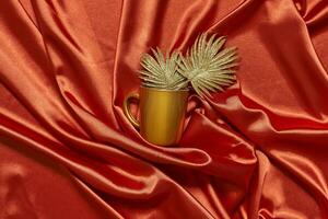 Decorative golden leaves on red textile backdrop photo