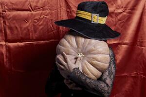 Halloween lady wearing witch cup and holding a big halloween pumpkin photo