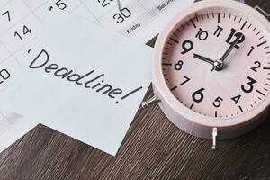 Deadline text on piece of paper, alarm clock and monthly calendar photo