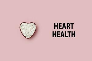 Heart health pills on pink photo