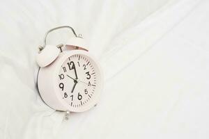 Alarm clock on white bed photo