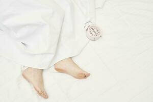 A clock and feet of a sleeping woman photo