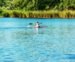 Dnipro, Ukraine - 06.20.2023 Technique of rowing of a single athlete on a kayak. Paddle splash motion. photo