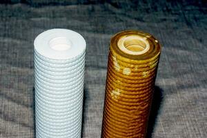 Used water filters with traces of dirt, clay and impurities and clean filters, prepared for replacement. Replacing multi-stage water filter cartridges. photo