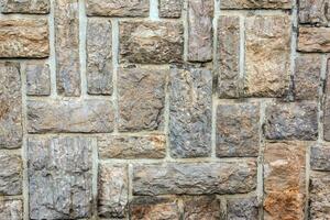 Cobble brown stone siding tile wall abstract background. House exterior with blocks tiled with cement . Crafted brickwork outer wall. photo