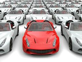 Fiery red sports car at front and center of many white sports cars photo