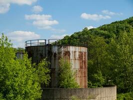 Abandoned rusty metal silo with concrete wall surrounding it photo