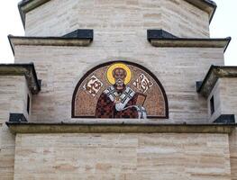 Delicate mosaic of St.Nicholas on small stone church doorway photo