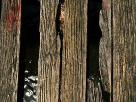 Old worn out and broken wood boards on a bridge over a small river photo