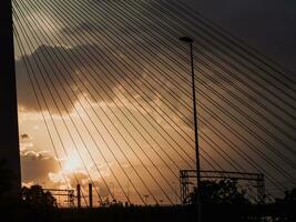 Dusk seen through the suspension cables of the bridge - industrial chimneys in the background photo