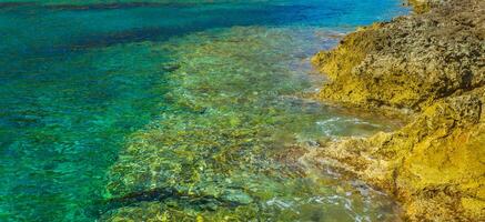 Crystal clear turquoise water near yellow rock shore photo