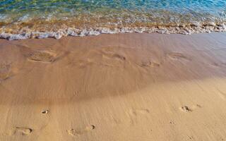 Footprints on the sandy beach being washed away photo