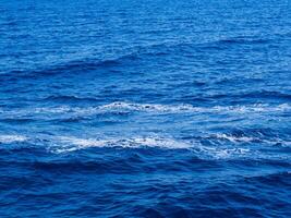 Straight boat wake left on the deep blue surface of the sea photo