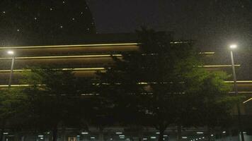 Rain falls on dark sky under modern building, beautiful lights video