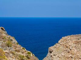 View of endless blue sea, two rocky hills meet in the foregorund photo