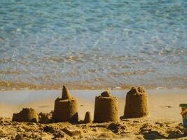 Small simple sand castles on an empty beach photo