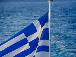 Flag of Greece in the wind and beautiful sea in the background photo