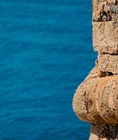 Orange stone wall of medieval fortress - blue sea in the background photo