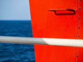 Red railing steps on a ship - high contrast image - white handle bar in the foreground photo