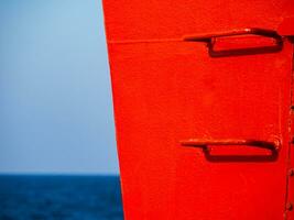 Red railing steps on a ship - high contrast image - sky and sea in the background photo