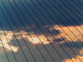 Sun setting behind the clouds seen through the cables of the suspension bridge photo