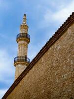 Minaret of medieval mosque towering over the wall in the old part of Rethymno - Crete, Greece photo