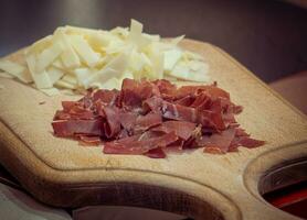 Sliced cheese and beef prosciutto on a cutting board photo