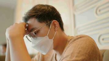 närbild av asiatisk man bär en mask chattar på en smartphone, oroande handla om hans liv. video