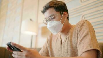 Male user sitting at shopping center in medical mask quarantine rules Businessmen chatting online, watching videos