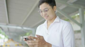 Man in a good mood plays with a cell phone under a building. video