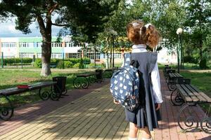 alumno con mochila y en un colegio uniforme en colegio yarda espalda a el marco. espalda a escuela, septiembre 1. un contento alumno. primario educación, elemental clase. la carretera a vida, a conocimiento foto